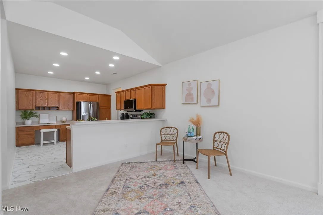 Kitchen featuring brown cabinetry, light colored carpet, recessed lighting, a peninsula, and light countertops