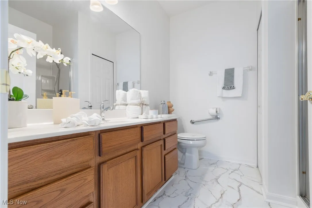 Bathroom featuring vanity, light marble finish floors, a closet, and a shower with shower door