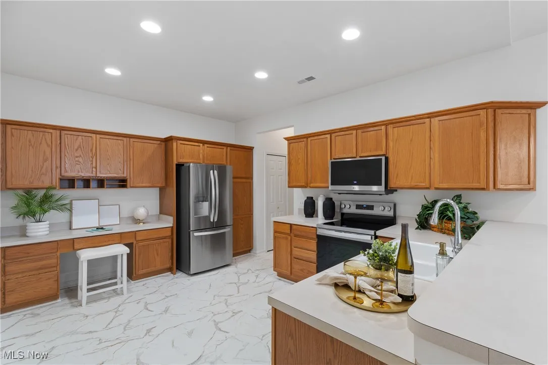 Kitchen featuring brown cabinetry, light countertops, stainless steel appliances, and recessed lighting