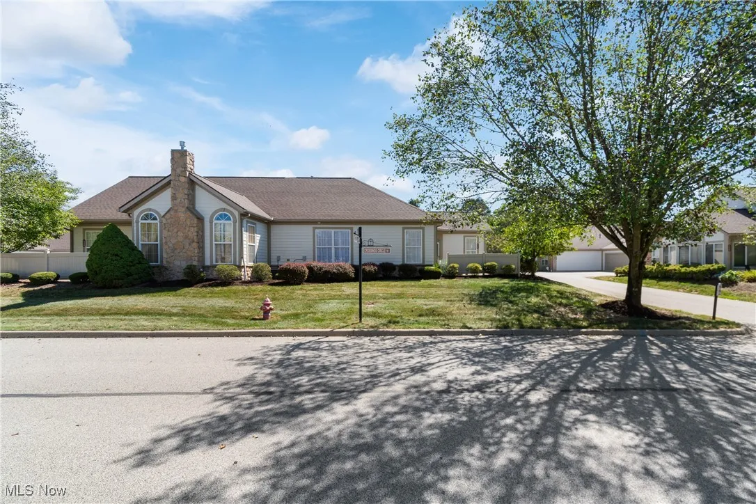 Ranch-style home featuring a front yard, a chimney, driveway, and a garage