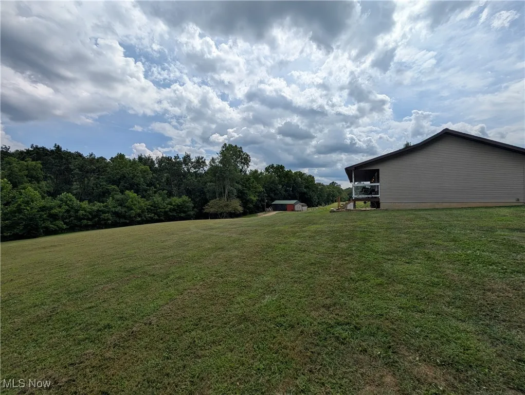 View of green lawn with a sunroom and a storage unit