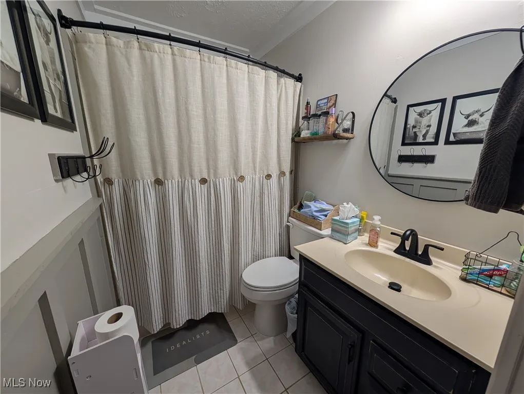 Bathroom featuring vanity, light tile patterned floors, a textured ceiling, a shower with curtain, and crown molding