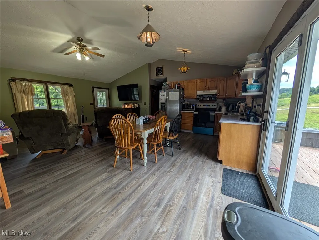 Dining space with a ceiling fan, light wood finished floors, lofted ceiling, a textured ceiling, and a chandelier