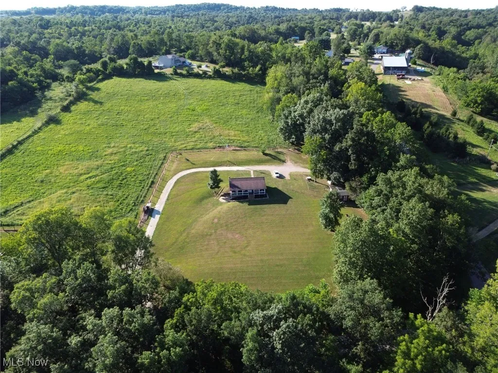 Aerial view of property's location featuring rural landscape and a heavily wooded area