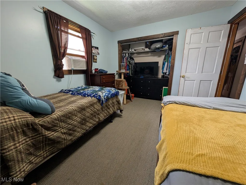 Bedroom featuring carpet, a closet, a textured ceiling, and cooling unit