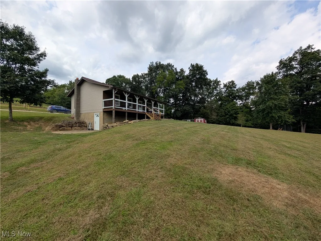 View of grassy yard featuring a storage shed and a deck