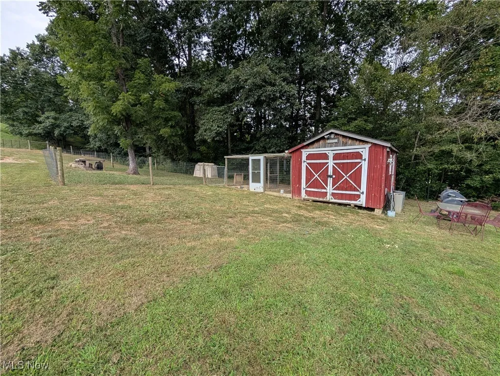 View of yard with view of wooded area and a storage unit
