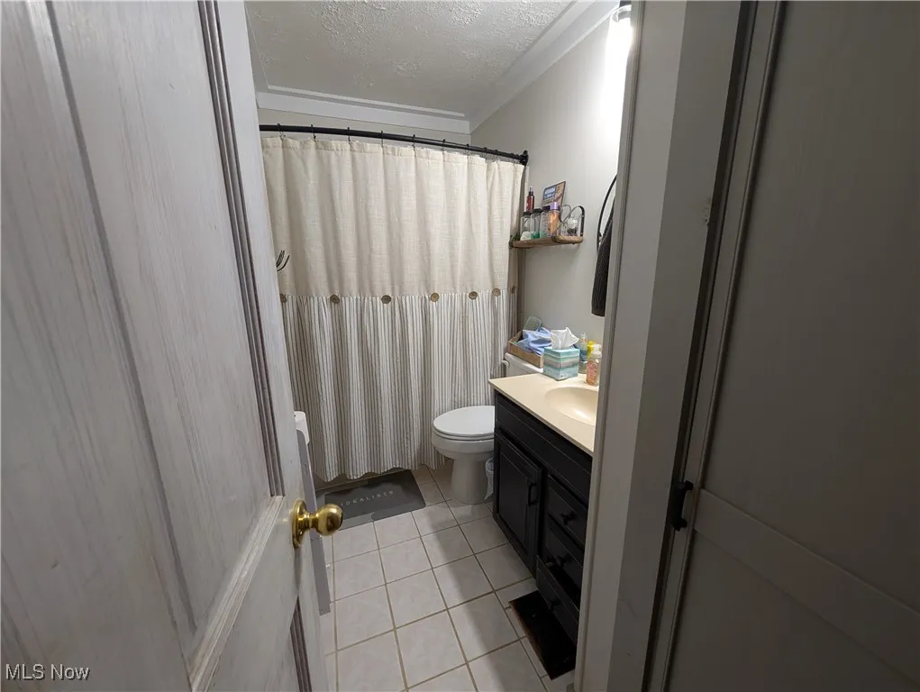 Full bath featuring light tile patterned floors, vanity, a textured ceiling, and a shower with shower curtain