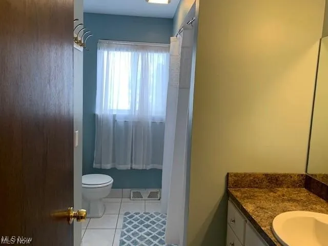 Full hall bathroom with combination shower/tub, light tile floors and vanity