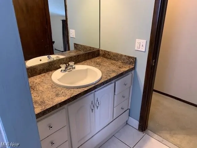 Hall bathroom featuring vanity and light tile patterned floors