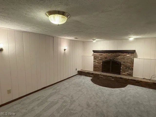 Family room with new carpet, paneled walls, a brick fireplace, and a textured ceiling