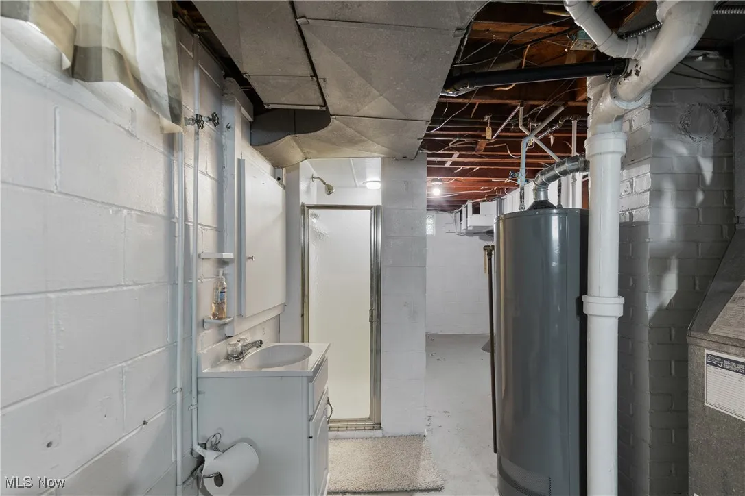 Unfinished below grade area with water heater and a sink