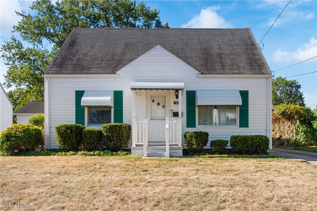View of front facade with a front yard, a shingled roof, and a porch