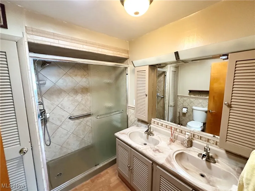 Full bathroom with a shower stall, vanity, and a closet