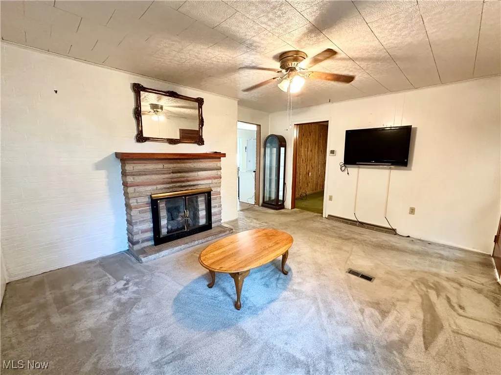 Living room with carpet floors, fireplace, and a ceiling fan