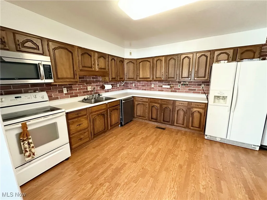 Kitchen featuring appliances, sink, and wood-style floors
