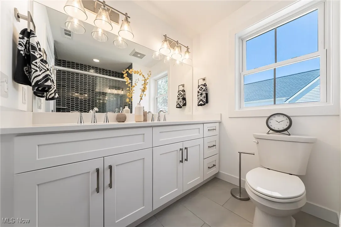Full bath featuring light tile patterned floors, double vanity, and a shower stall