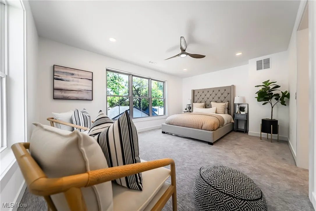 Carpeted primary bedroom with recessed lighting and ceiling fan