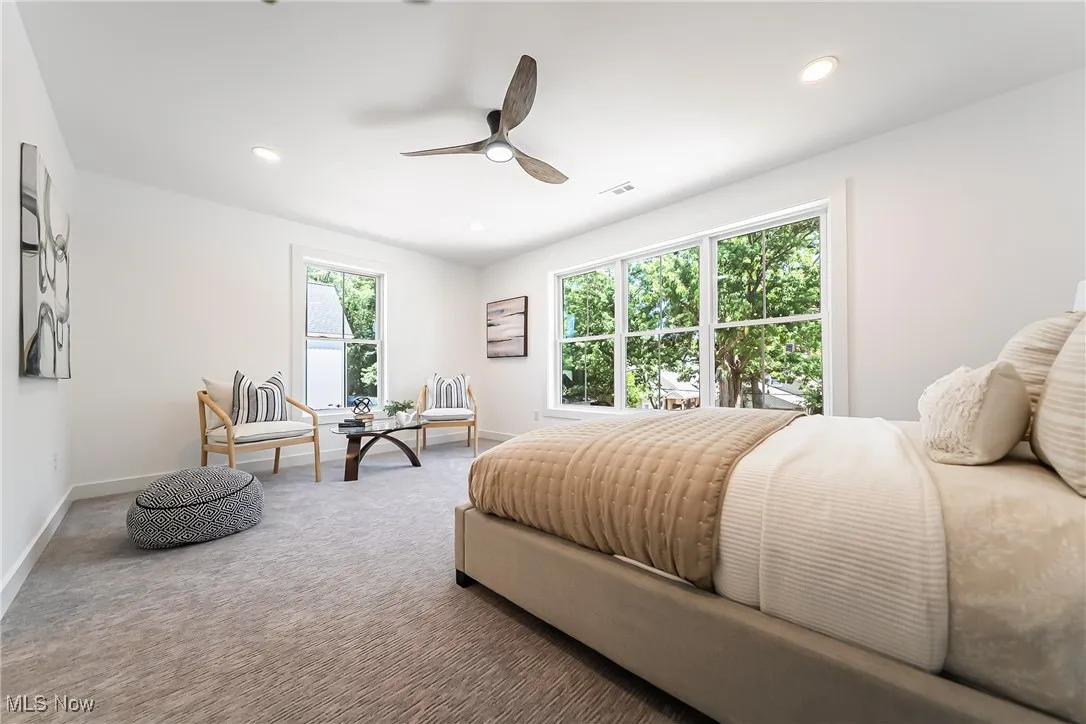 Carpeted primary bedroom with ceiling fan and recessed lighting