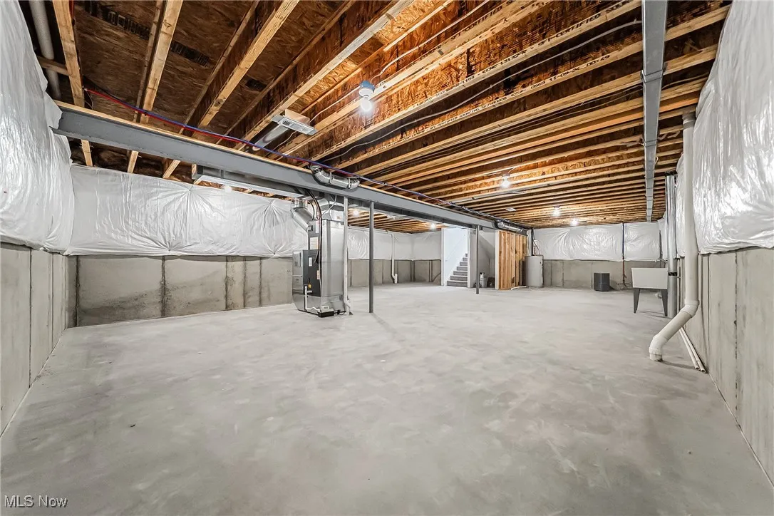 Unfinished basement with stairs and heating unit