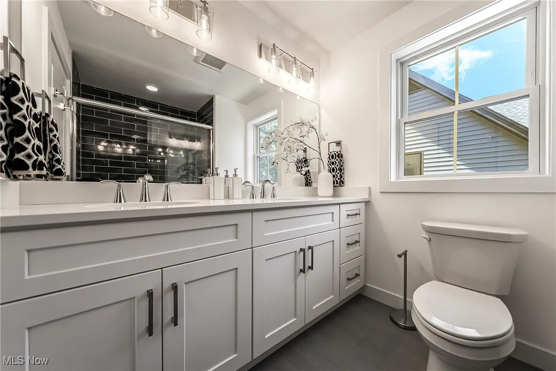 Full bath featuring double vanity and a stall shower
