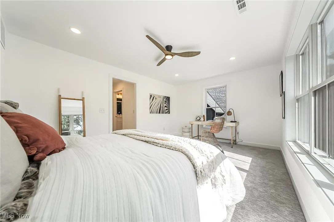 Primary bedroom with multiple windows, light carpet, a ceiling fan, and recessed lighting