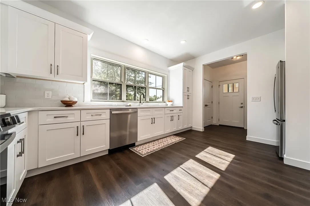 Kitchen with white cabinets, stainless steel appliances, dark wood-style flooring, and recessed lighting