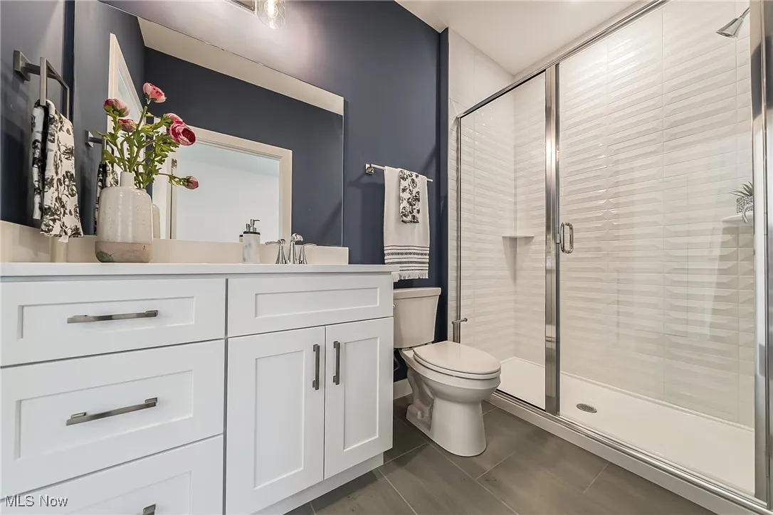 Bathroom featuring a shower stall, vanity, and tile flooring