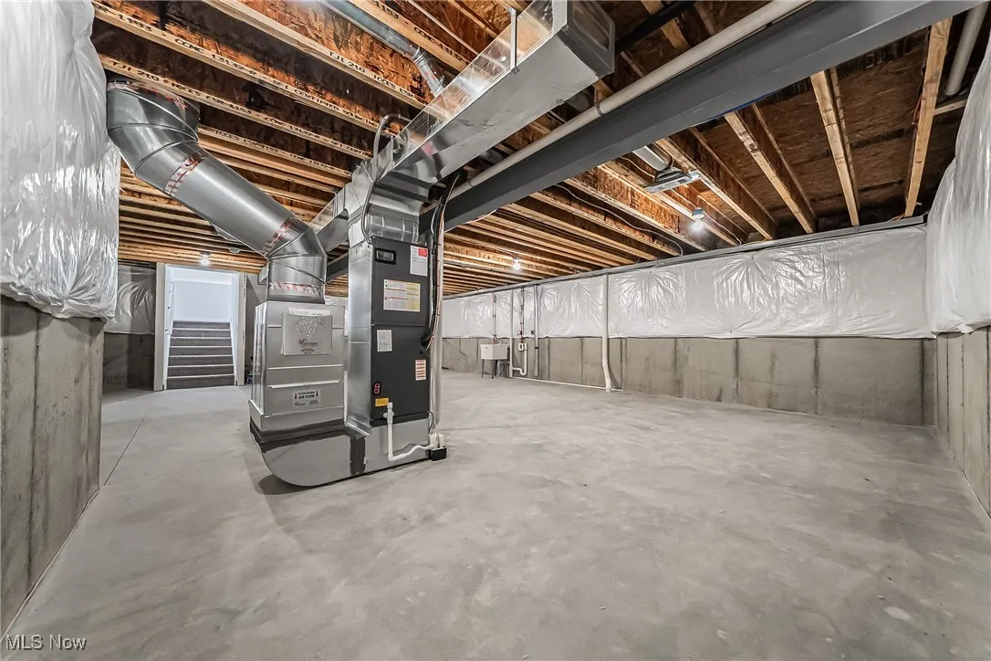 Unfinished basement with heating unit and stairway
