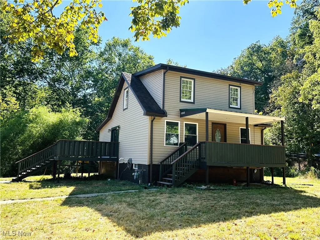 Front view of home with stairway, a yard, a front porch and a side deck