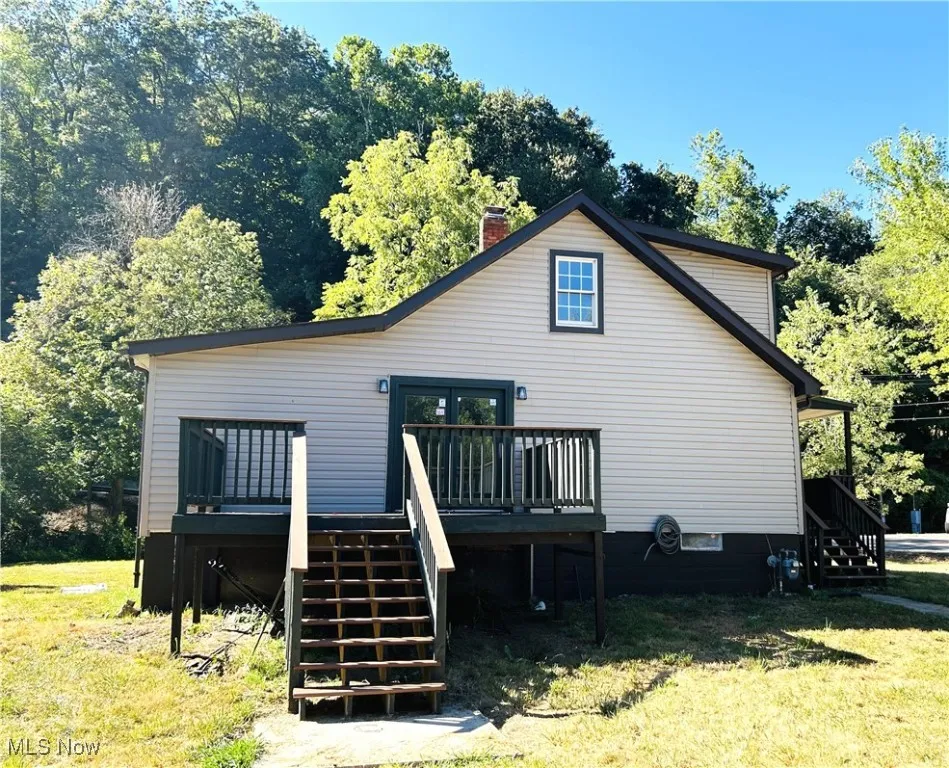 Side view of home featuring stairway, a deck, and a lawn