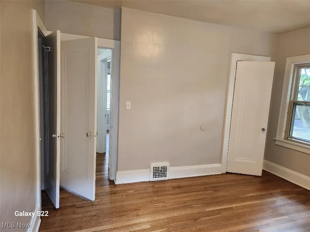 Unfurnished bedroom with dark wood-type flooring
