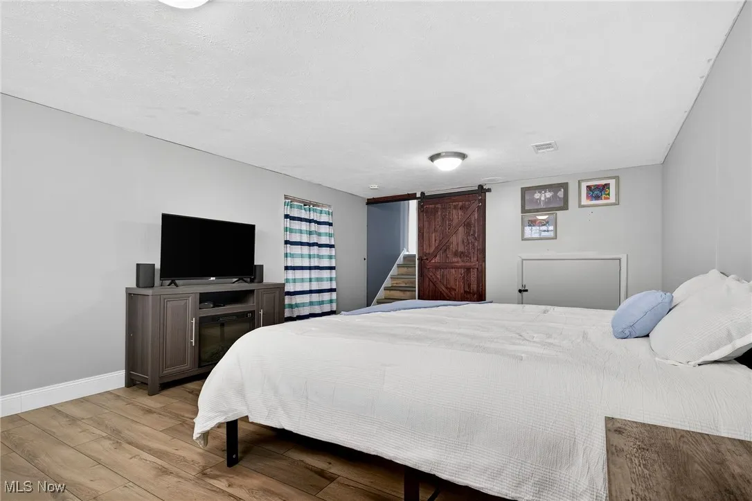 Bedroom featuring a barn door and wood finished floors
