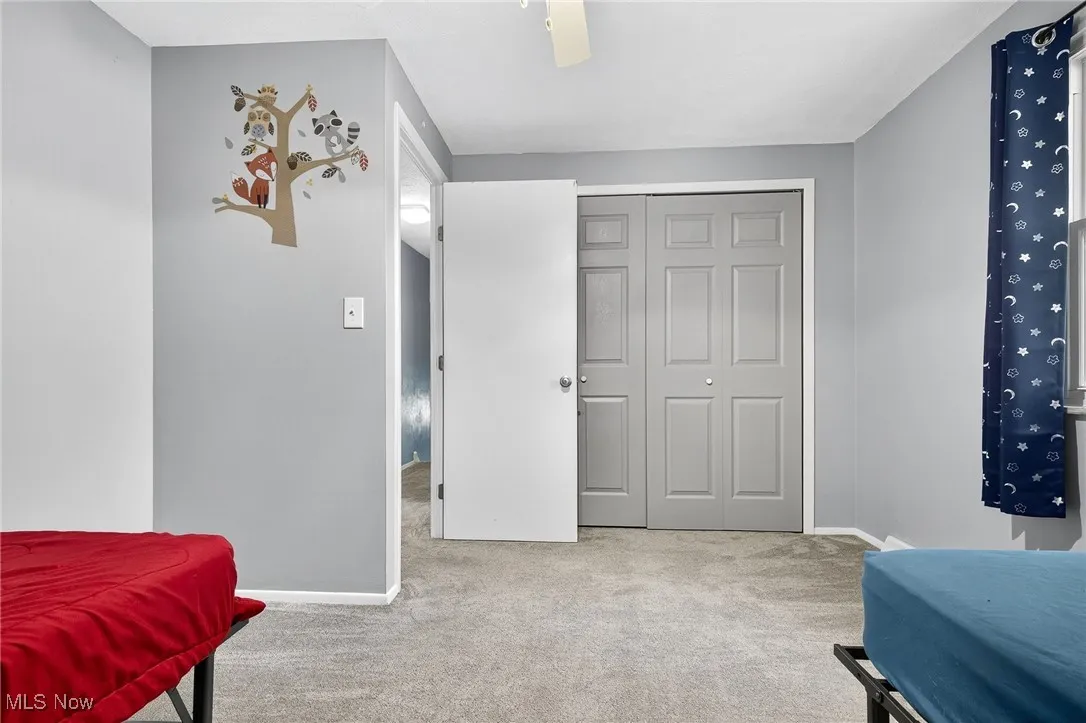 Bedroom featuring light colored carpet, a closet, and a ceiling fan