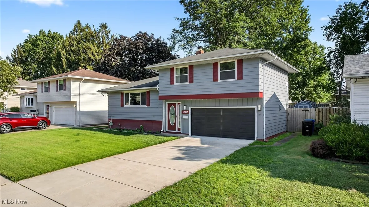 Split level home featuring driveway, a garage, and a chimney