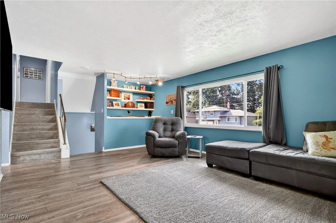 Living area with stairs, wood finished floors, a textured ceiling, and track lighting