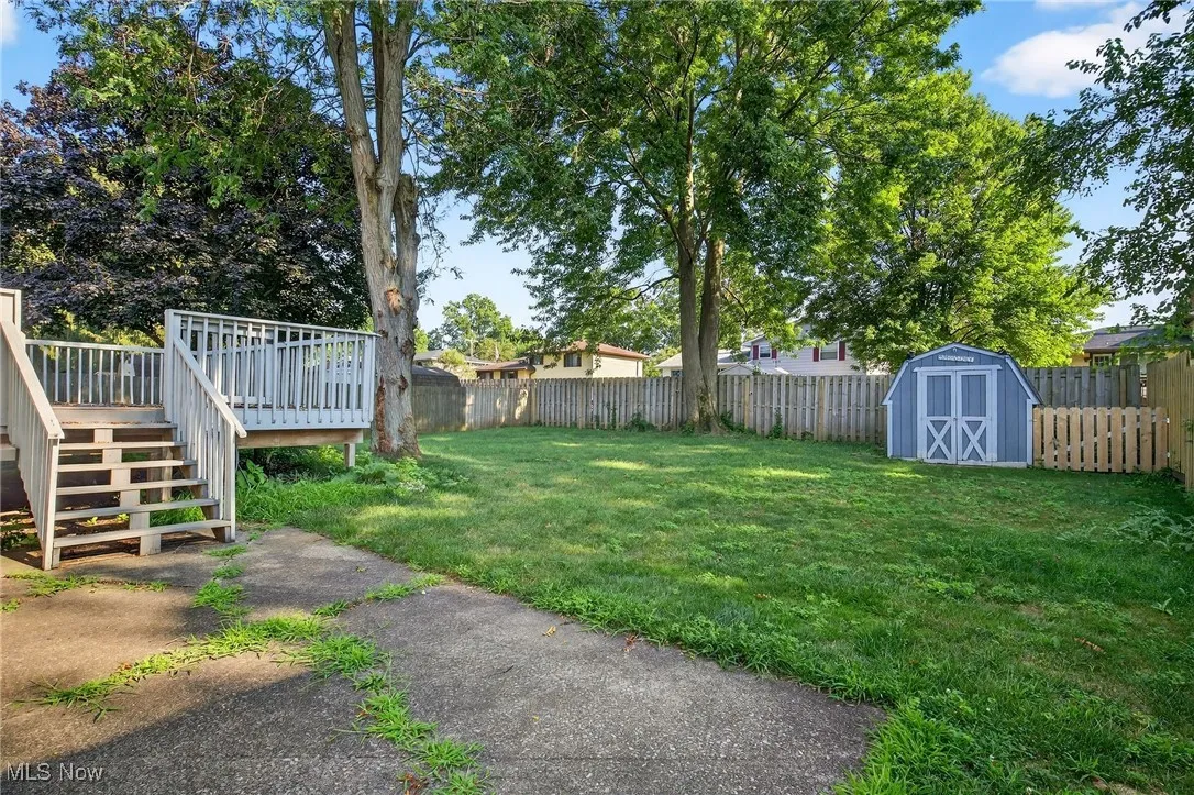 Fenced backyard with a deck, and a storage unit