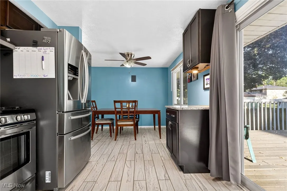Kitchen with stainless steel range with gas stovetop, light wood-style flooring, dark brown cabinetry, light stone countertops, and ceiling fan