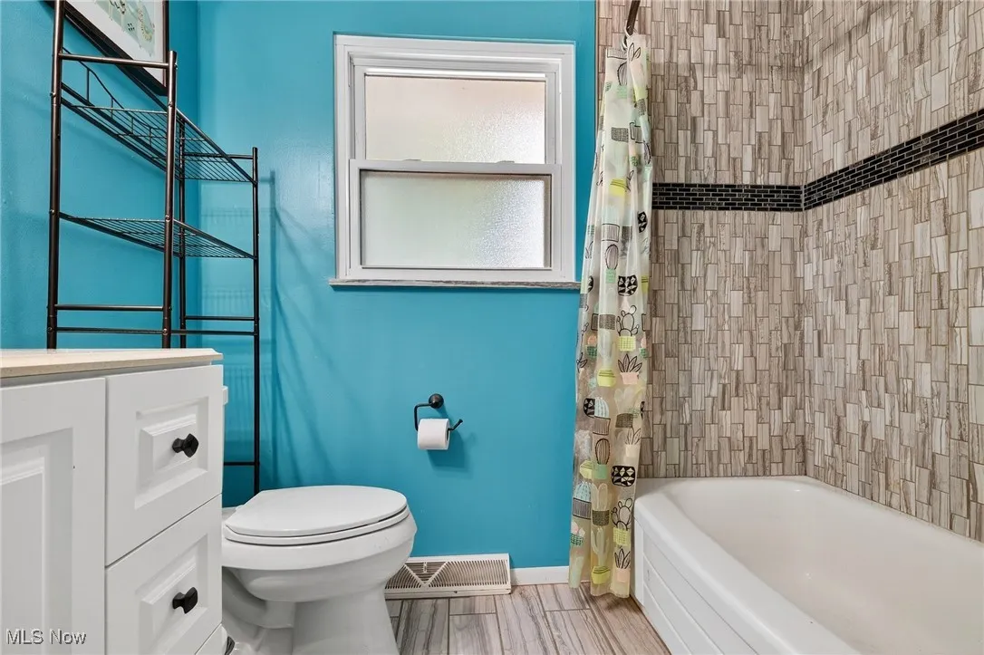 Full bathroom with shower / tub combo, vanity, and wood finish floors