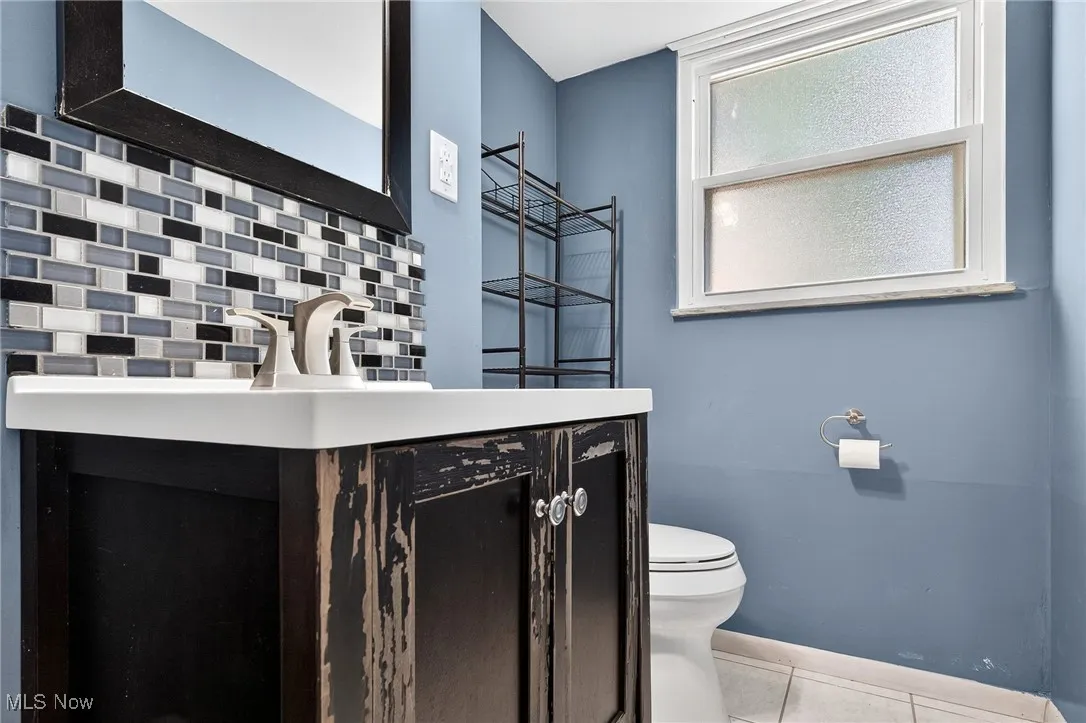 Half bath featuring vanity, light tile patterned floors, and tasteful backsplash
