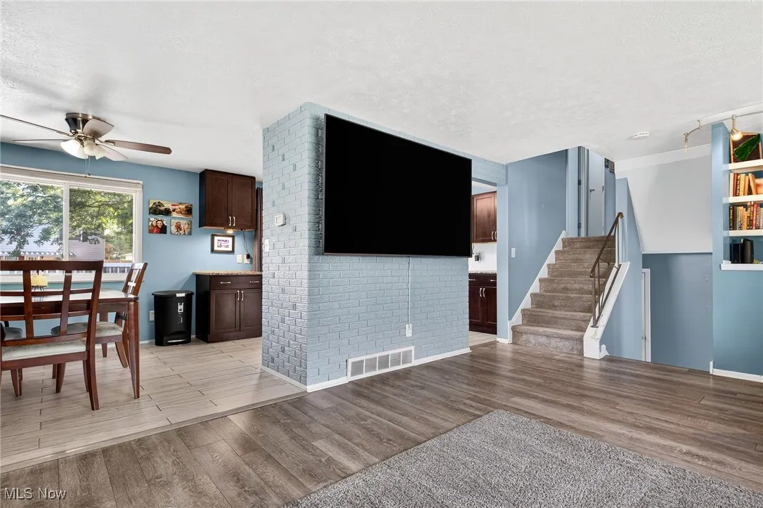 Unfurnished living room featuring light wood-style floors, stairs, a textured ceiling, and ceiling fan