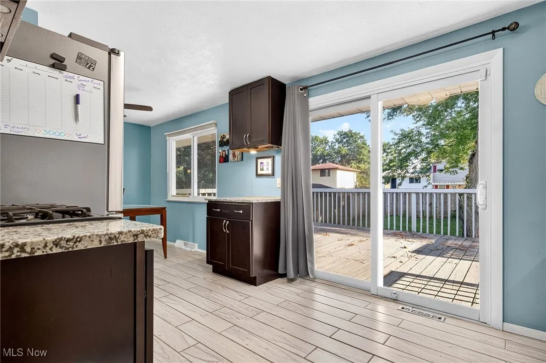 Kitchen featuring dark brown cabinetry, wood tiled floors, plenty of natural light, and light stone countertops