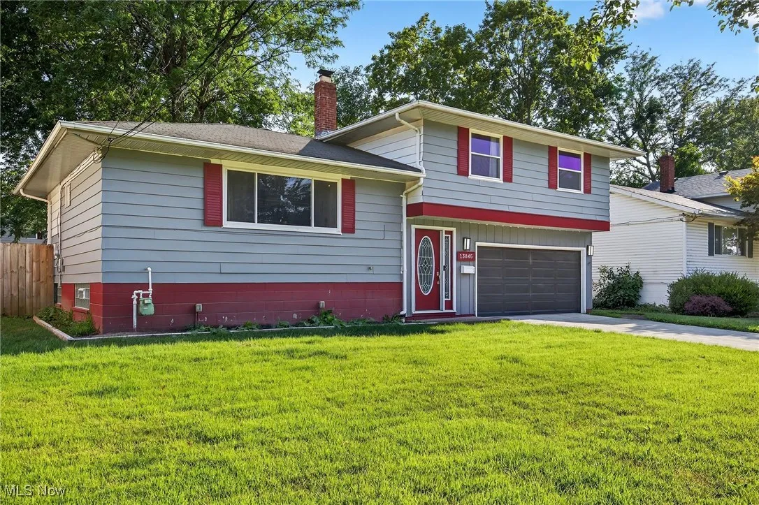 Split level home with an attached garage, a chimney, concrete driveway, and a shingled roof