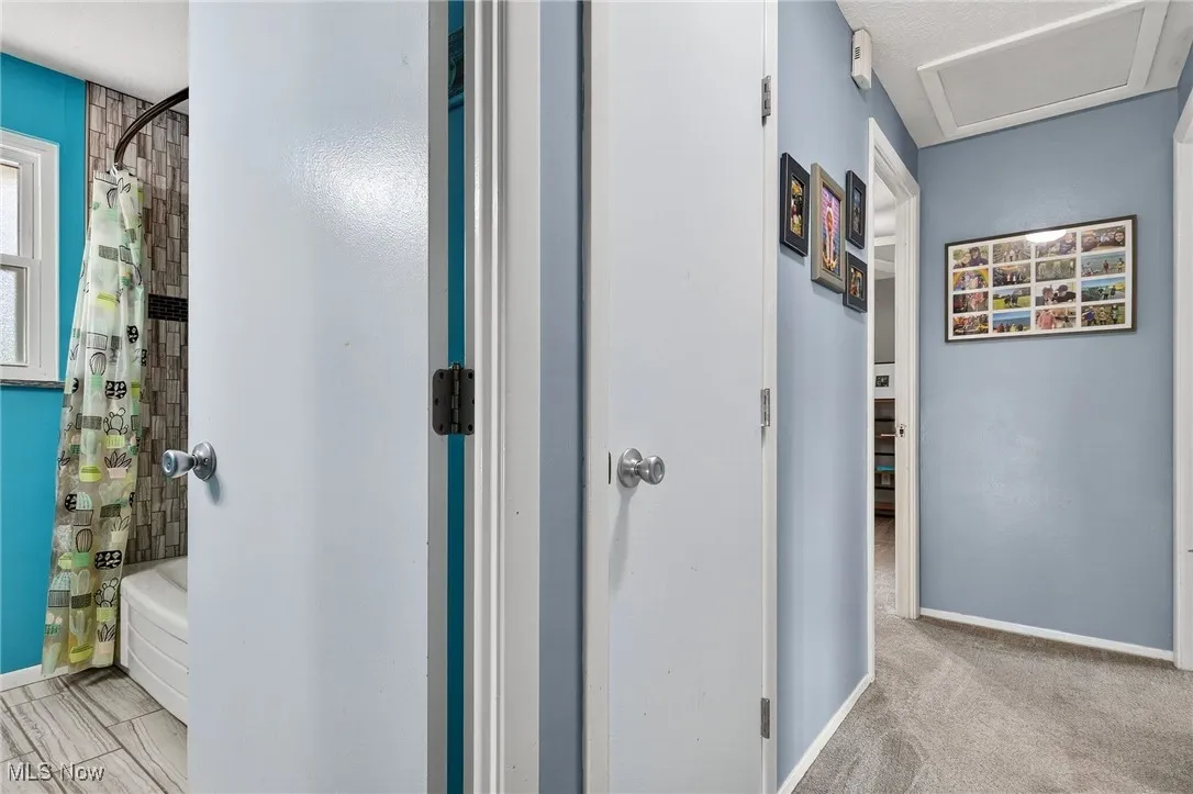 Hall featuring baseboards and attic access