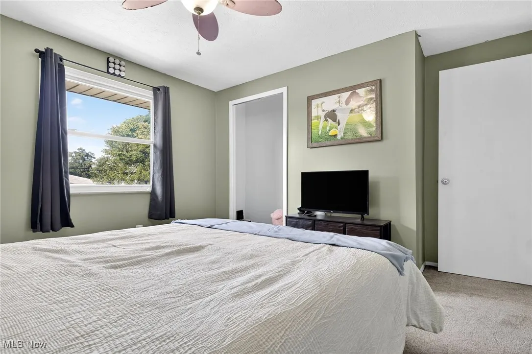 Carpeted bedroom featuring ceiling fan