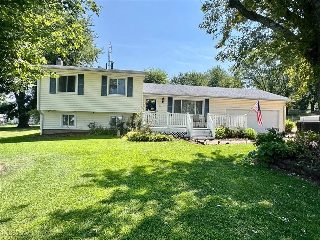 Tri-level home featuring a garage, a front yard, and a wooden deck
