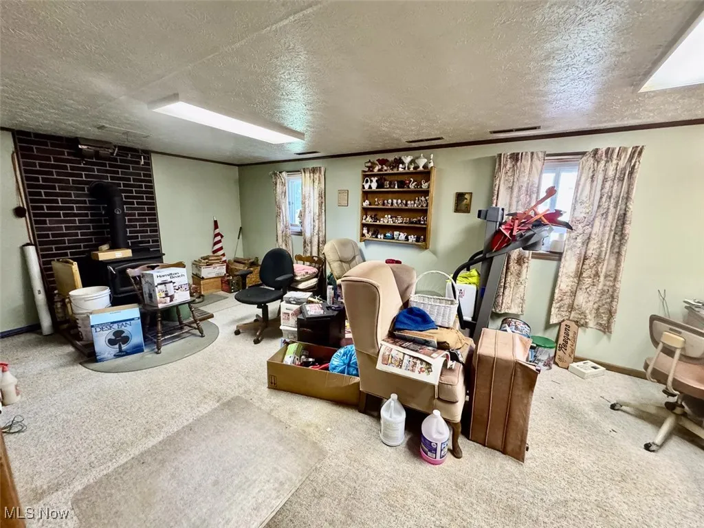 Basement with a wood stove, a textured ceiling, and carpet