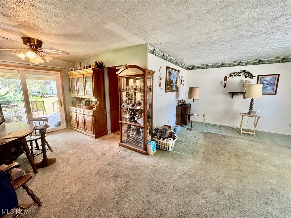 Living area with light carpet, a textured ceiling, and ceiling fan