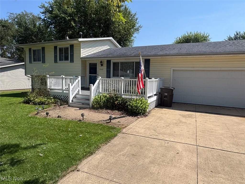 Tri-level home with driveway, a garage, a front yard, a shingled roof, and a deck