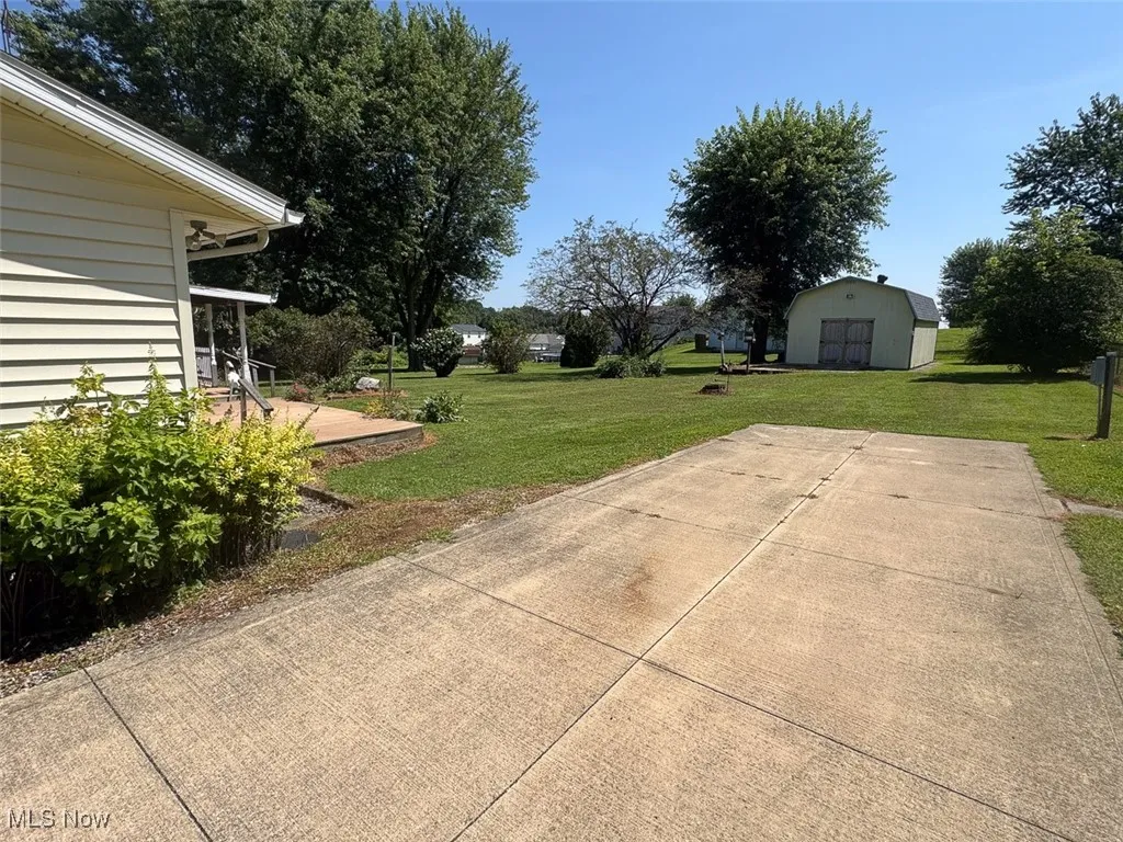 View of patio featuring a detached garage, driveway, and a storage unit